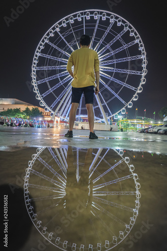 Young man looking Ferris wheel at night market Asiatique ,Bangkok Thailand