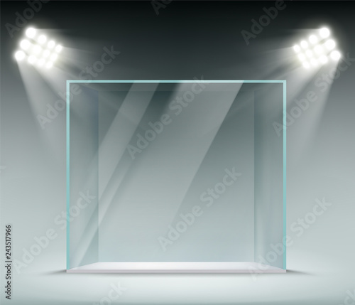 Glass transparent cube illuminated by spotlights. Showcase for the sale of goods.