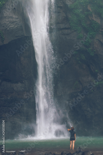 Young woman posing on a great Sekumpul waterfall in the deep rainforest of Bali island  Indonesia.