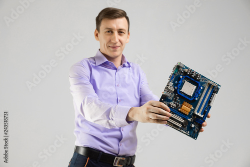 young man with motherboard in his hands is isolated on light background photo