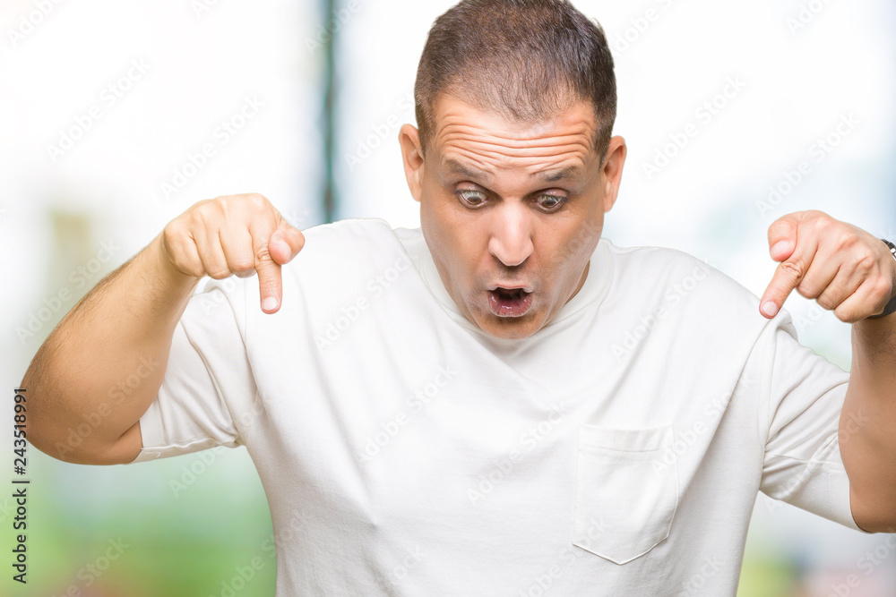 Middle age arab man wearig white t-shirt over isolated background Pointing down with fingers showing advertisement, surprised face and open mouth Middle age arab man wearig white t-shirt over isolated background Pointing down with fingers showing advertisement, surprised face and open mouth