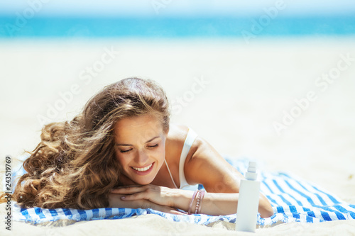 woman with sun block laying on striped towel on seashore photo