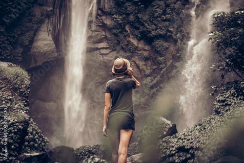 Young woman posing on a great Sekumpul waterfall in the deep rainforest of Bali island  Indonesia.