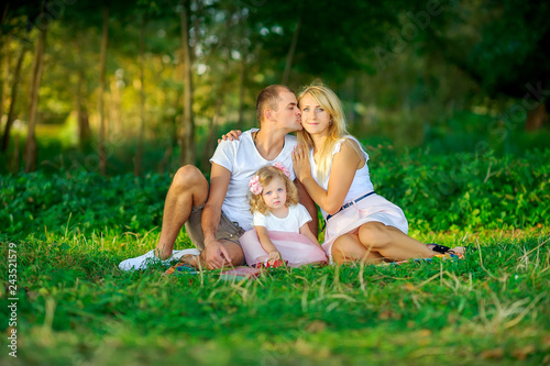 happy family in the evening park, sit on the grass and hug