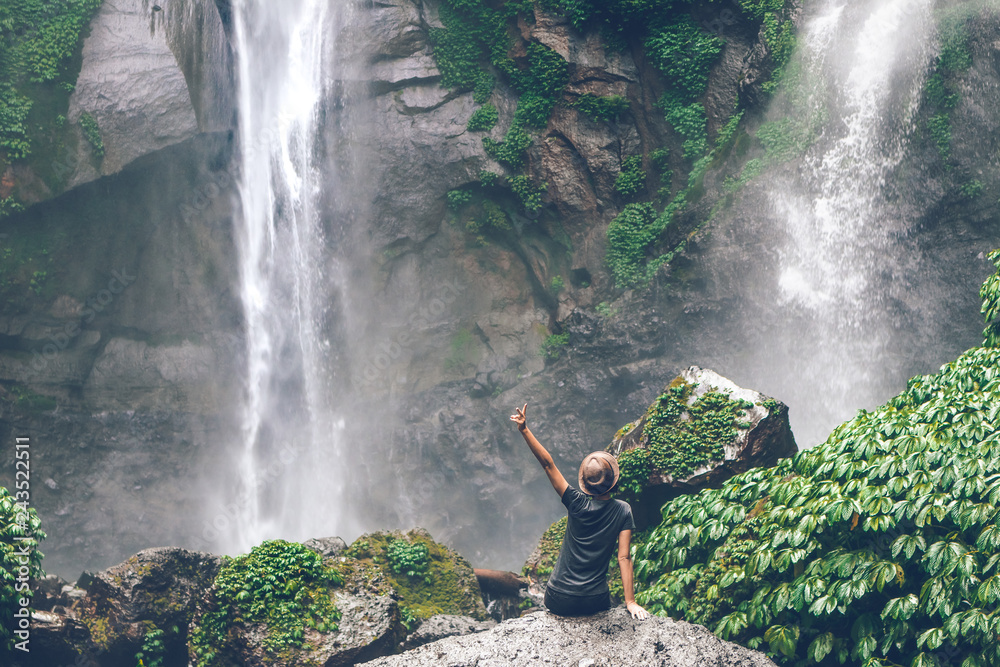Young woman posing on a great Sekumpul waterfall in the deep rainforest ...