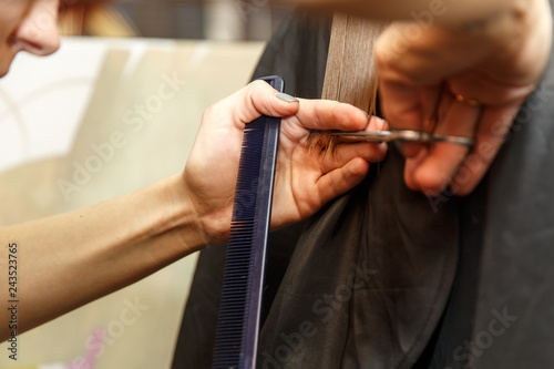 Professional hairdresser dyeing hair of her client in salon. Haircutter cuting hair. Selective focus.