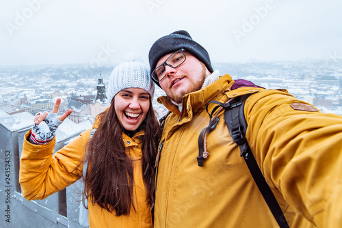 couple tourists taking selfie with beautiful city view in winter time on background © phpetrunina14