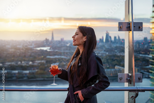 Photography Attraktive Frau genießt einen Drink in einer Bar über der Skyline von London nac