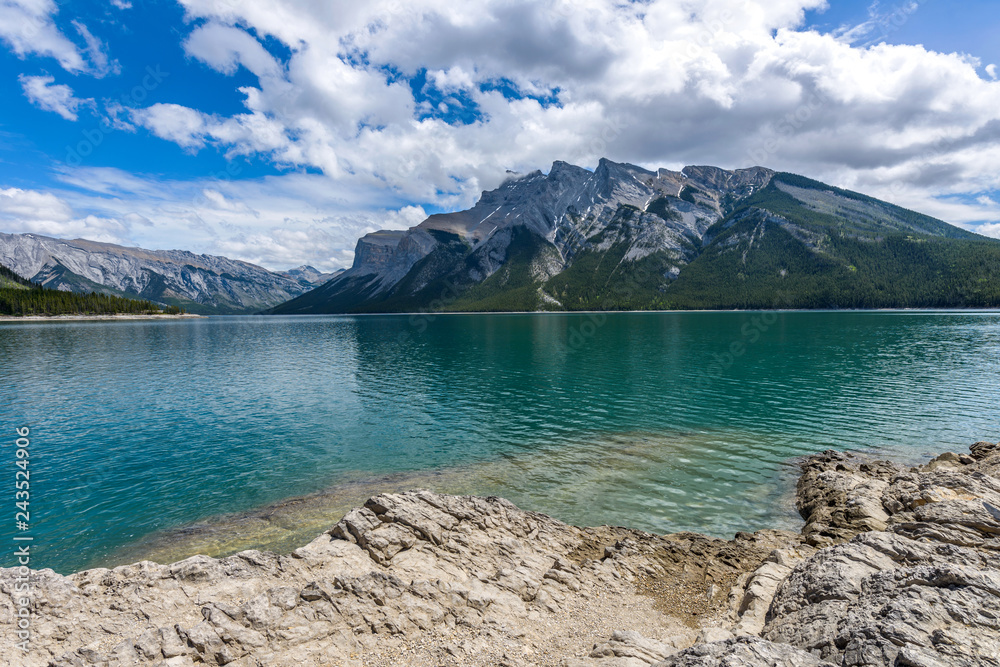 Spring at Lake Minnewanka - A Spring view of colorful Lake Minnewanka, surrounded by rocky shores and rugged mountain peaks, Banff National Park, Alberta, Canada.