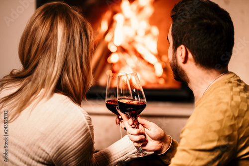 Φωτογραφία Chill couple having wine drinks and looking at fire burning in fireplace, in cos