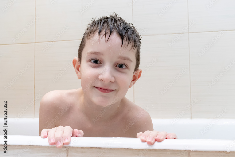 An eight year old boy sitting in bath and smiling An eight year old boy sitting in bath and smiling