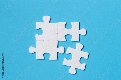 Four blank white puzzle pieces on blue background