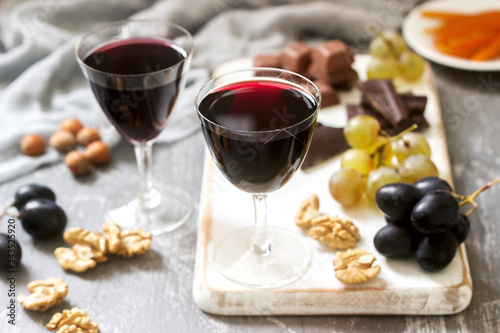 Creme de Cassis homemade liqueur served with grapes, nuts and chocolate. Rustic style. photo