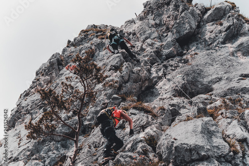 Image of young man mountaineer climbing on a rock in the mountains