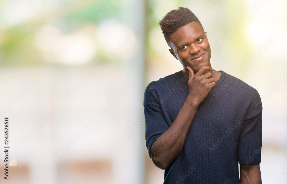 Obraz premium Young african american man over isolated background with hand on chin thinking about question, pensive expression. Smiling with thoughtful face. Doubt concept.