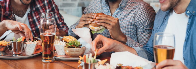 Three men enjoying burgers and beer in bar