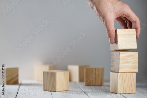 Hand putting a wooden cube on top of other cubes
