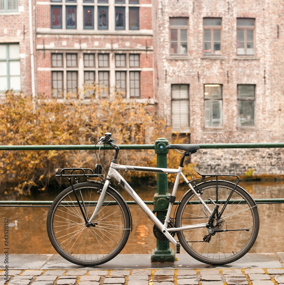 Bicycles standing near canal with European building on a autumn day.