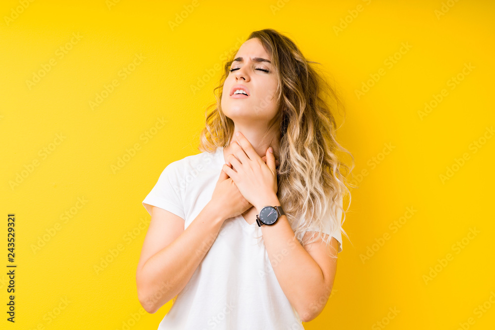 Young beautiful blonde woman over yellow background shouting and suffocate because painful strangle. Health problem. Asphyxiate and suicide concept.