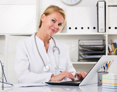 young female doctor working on computer in home office