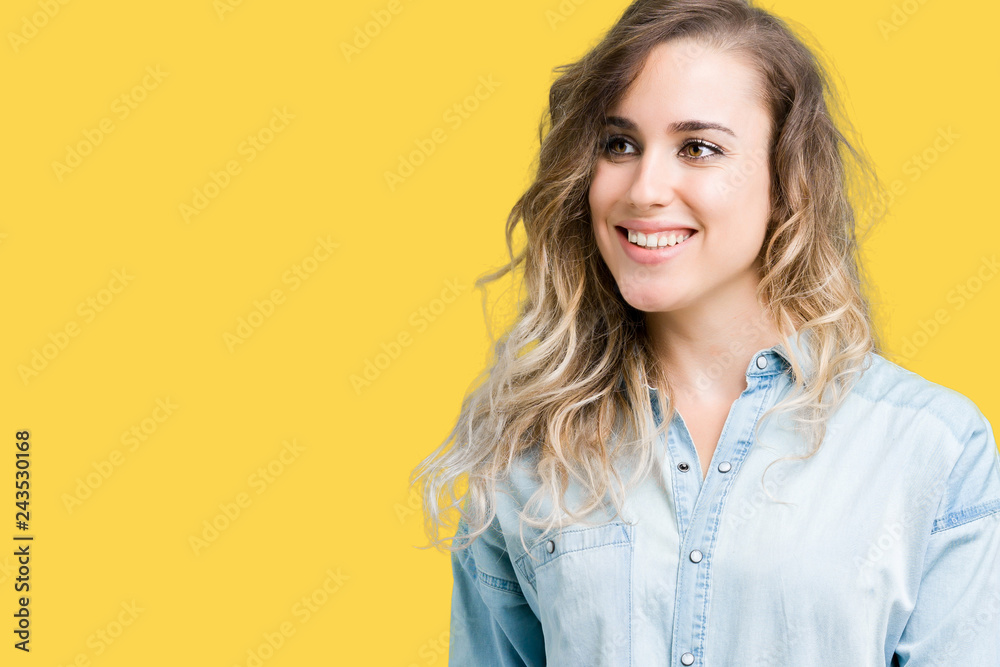 Beautiful young blonde woman over isolated background looking away to side with smile on face, natural expression. Laughing confident. Beautiful young blonde woman over isolated background looking away to side with smile on face, natural expression. Laughing confident.