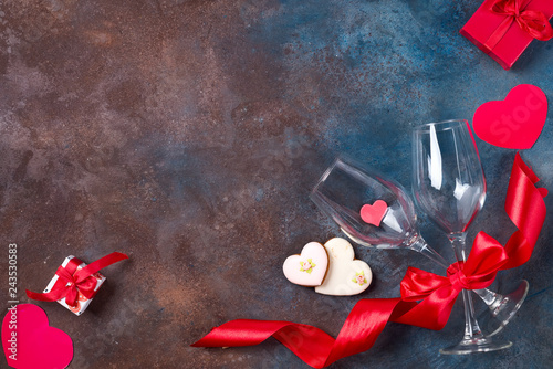 Composition with wine glasses, ribbon and decorative hearts on stone background with copy space, flat lay.