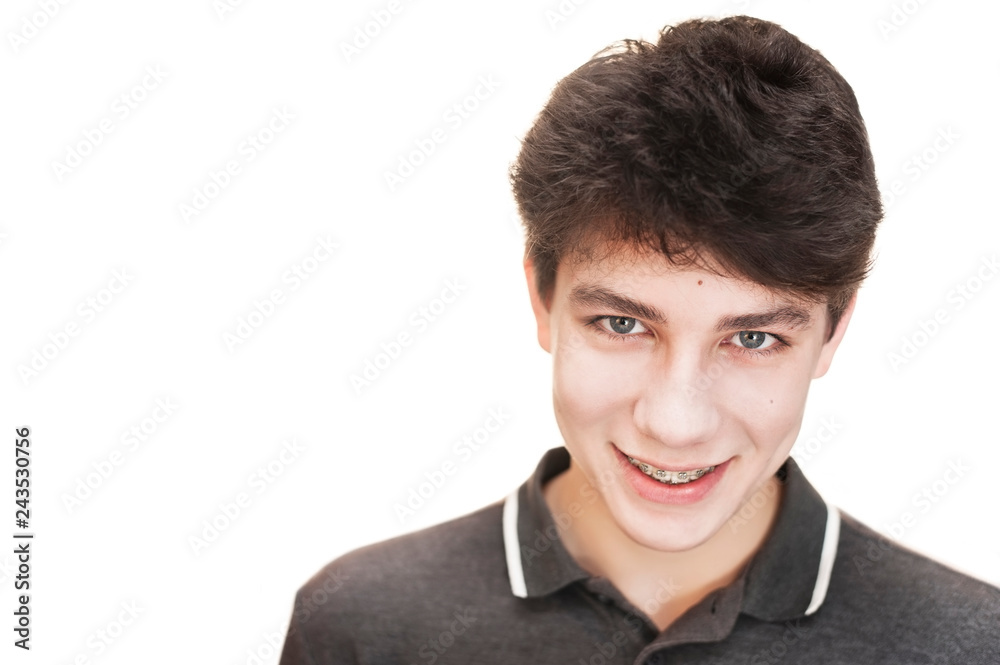 Handsome teen cute smiles on a white background. The guy on his teeth is setting the braces for leveling the teeth