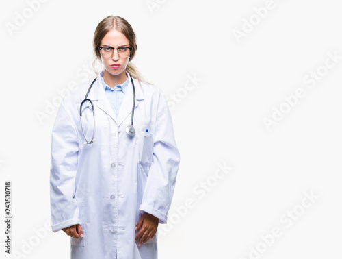 Beautiful young blonde doctor woman wearing medical uniform over isolated background skeptic and nervous, frowning upset because of problem. Negative person.