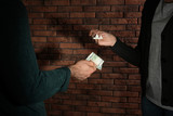 Man buying drugs from dealer near brick wall, closeup of hands