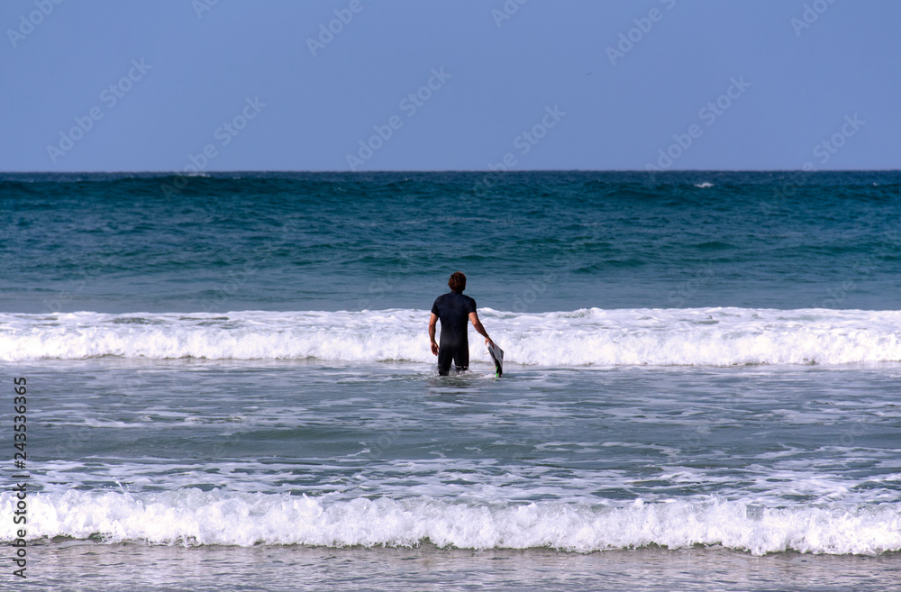 A surfer with his board going into the sea A surfer with his board going into the sea