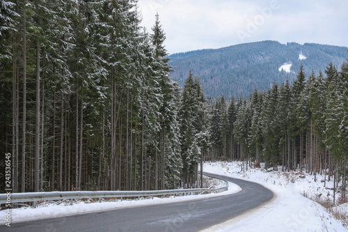Beautiful mountain landscape with snowy forest and asphalt road
