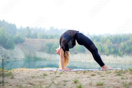 Attractive redhead curly woman or model practicing yoga outdoors