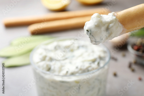Bread stick with cucumber sauce on blurred background, space for text. Traditional Tzatziki