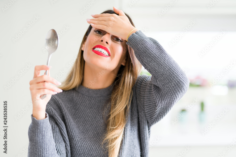 Young beautiful woman holding silver spoon at home stressed with hand on head, shocked with shame and surprise face, angry and frustrated. Fear and upset for mistake. Young beautiful woman holding silver spoon at home stressed with hand on head, shocked with shame and surprise face, angry and frustrated. Fear and upset for mistake.