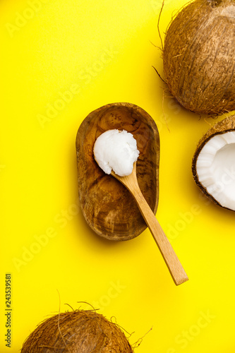 Spoon with coconut oil on yellow background
