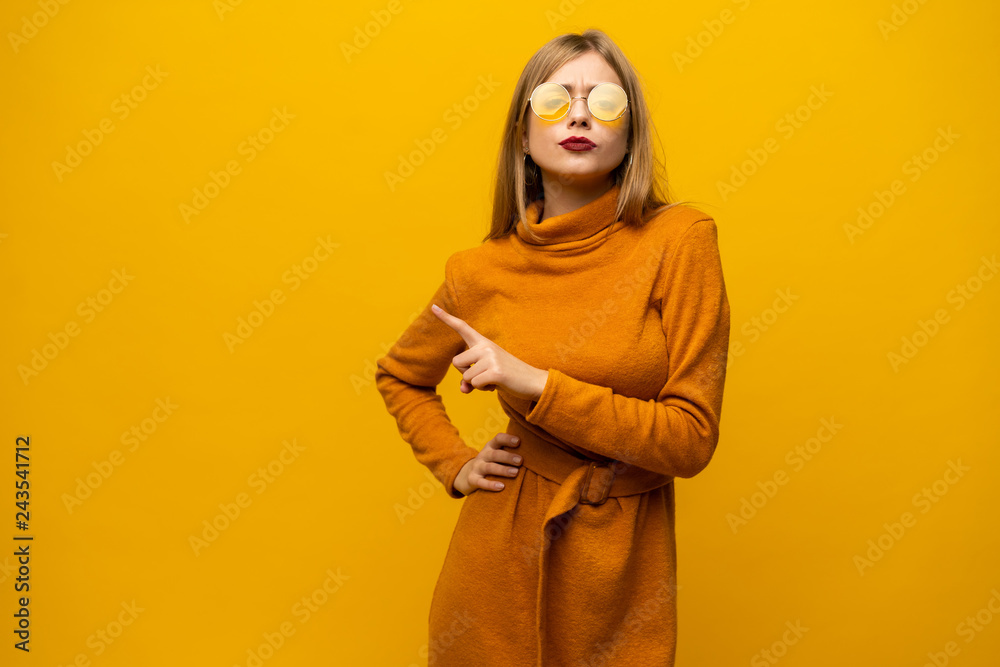 Cheerful lovely young woman standing and pointing away over yellow background. Cheerful lovely young woman standing and pointing away over yellow background.