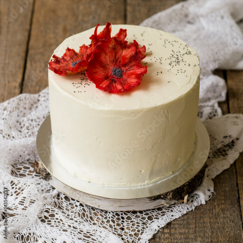 Beautiful White Poppy Seed cake with red pineapple poppy flowers. White cake on a wwooden background with lace fabric. Cake for Valentine's Day, Mother's Day or Women's Day. Close up,selective focus photo