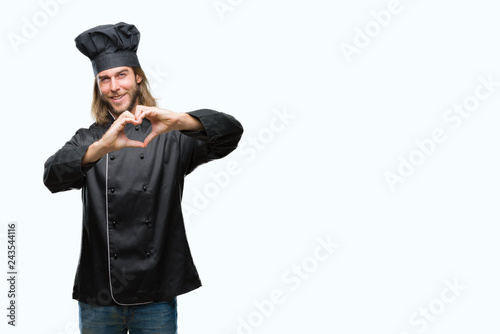 Young handsome cook man with long hair over isolated background smiling in love showing heart symbol and shape with hands. Romantic concept.