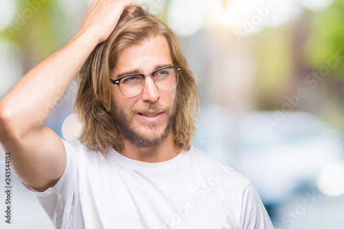 Young handsome man with long hair wearing glasses over isolated background confuse and wonder about question. Uncertain with doubt, thinking with hand on head. Pensive concept.