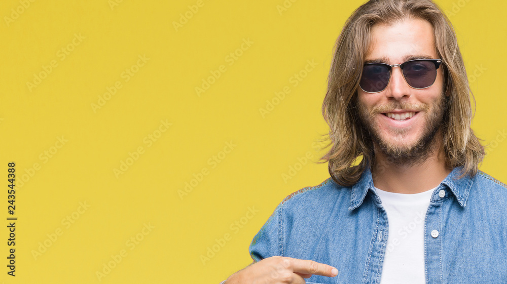 Young handsome man with long hair over isolated background sending message using smartphone with surprise face pointing finger to himself