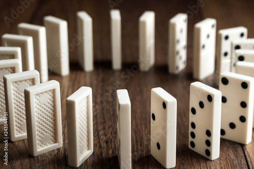Creative background, white domino, on brown wooden background. Concept of domino effect, chain reaction, risk management, copy space.