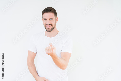 Young handsome man wearing casual white t-shirt over isolated background Beckoning come here gesture with hand inviting happy and smiling