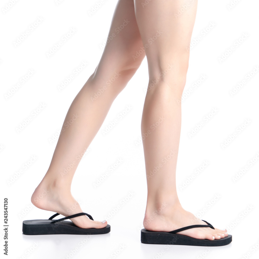Woman legs in black flip flops goes on white background isolation Woman legs in black flip flops goes on white background isolation