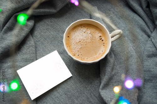 Warm weekend in cold weather. A cup of coffee on textile grey background with garland and copyspace. photo