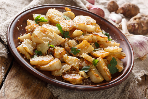 Spicy fried Jerusalem artichoke with garlic, cheese and parsley closeup on a plate. horizontal