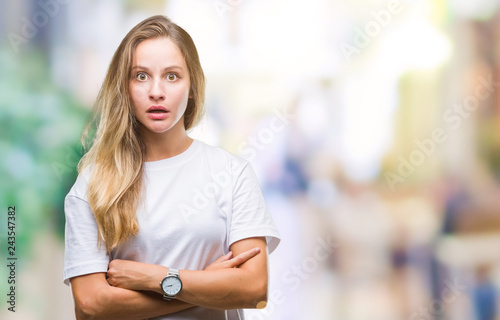 Fototapeta Naklejka Na Ścianę i Meble -  Young beautiful blonde woman wearing casual white t-shirt over isolated background afraid and shocked with surprise expression, fear and excited face.