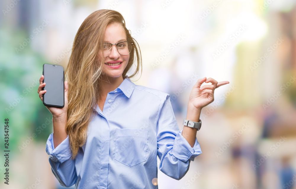 Young beautiful blonde business woman showing screen of smartphone over isolated background very happy pointing with hand and finger to the side