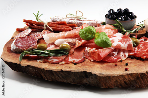 Marble cutting board with prosciutto  bacon  salami and sausages on wooden background. Meat platter
