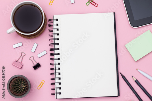 Top view workspace mockup on pink background with notebook, cactus, pen, pencil, cup of coffee, clips and accessories. Mockup