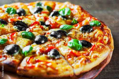 Pizza with Mozzarella cheese, Tomatoes, pepper, olive, Spices and Fresh Basil. Italian pizza. Pizza Margherita or Margarita on wooden table background
